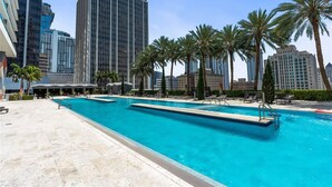 A swimming pool with lounge chairs, palm trees, and tall buildings in the background. - Biscayne Bay Views-pool, Hot Tub and Amenities (Miami)