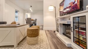 Una cucina moderna con TV integrata, una zona pranzo con sedie e un'accogliente area salotto con tappeto.