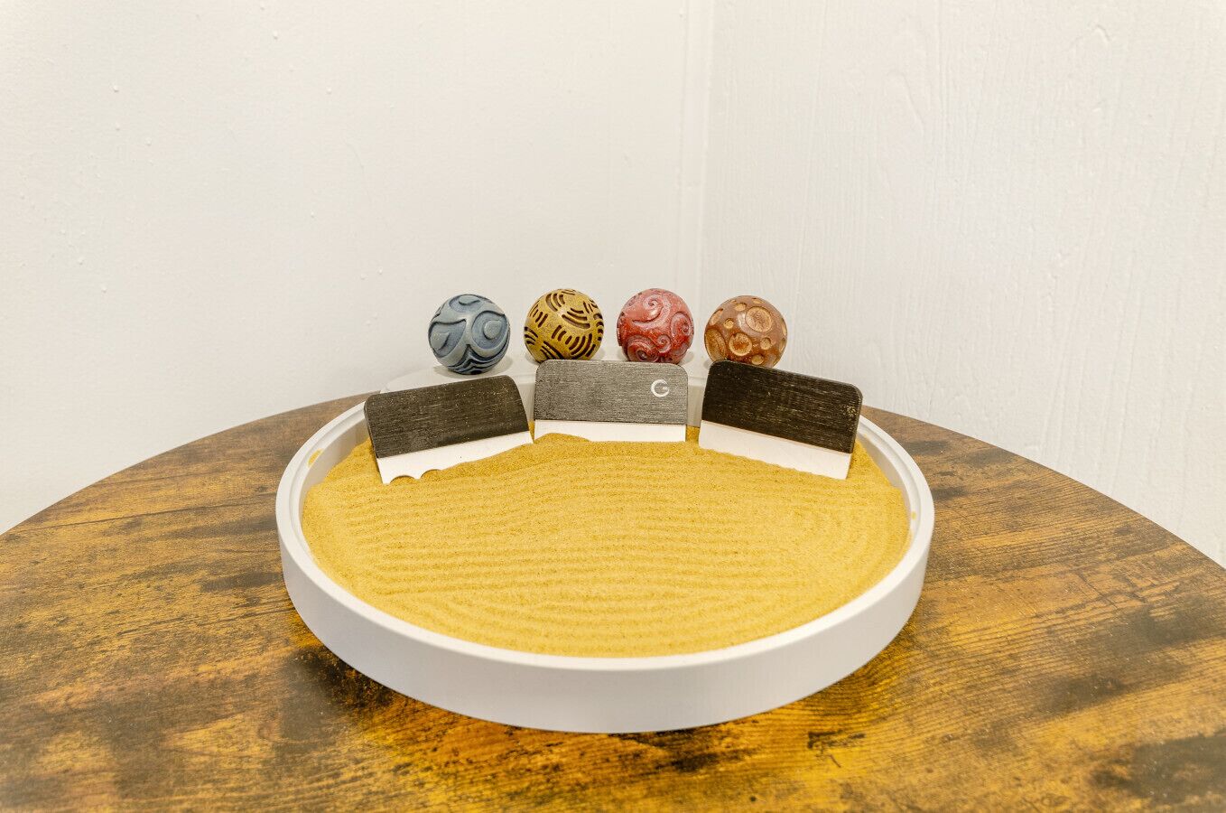 Uma bandeja redonda e branca com superfície texturizada, colocada sobre uma mesa de madeira.
