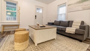 A living room with a grey sofa, a white coffee table, a woven pouf, and a patterned rug. - Zen Retreat Near Tacoma & Seattle (Tacoma)