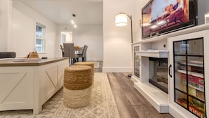 A modern kitchen with a built-in TV, a dining area with chairs, and a cozy seating area with a rug. - Zen Retreat Near Tacoma & Seattle (Tacoma)