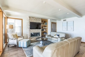 A living room with a stone fireplace, a sofa, a chair, and a coffee table. - 450c 3BR Apt Villa Exquisite (Dana Point)