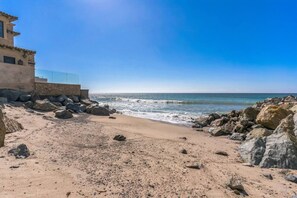 A beach with a building on the left, large rocks, and the ocean in the background. - 450c 3BR Apt Villa Exquisite (Dana Point)