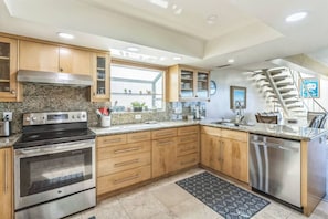 A modern kitchen with granite countertops, stainless steel appliances, wooden cabinets, and a built-in dishwasher. - 450c 3BR Apt Villa Exquisite (Dana Point)