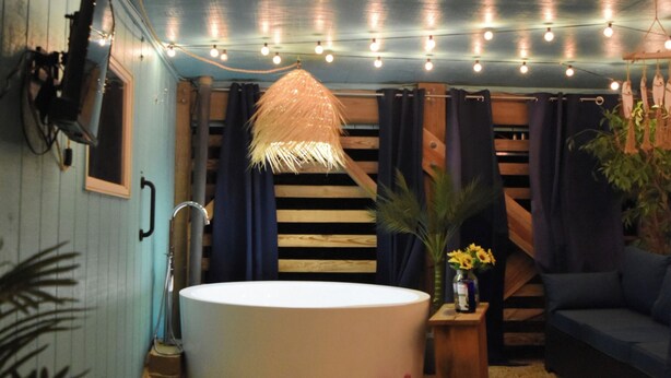 A cozy, rustic bathroom with a bathtub, wooden beams, and string lights. - Walk to Beach, Jacuzzi, Treetop Deck, 4WD Pass, Love Pets! (Corolla)