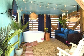 Ein gemütlicher Innenraum mit einer großen weißen Badewanne, einem blauen Sofa und einem weißen Sessel.