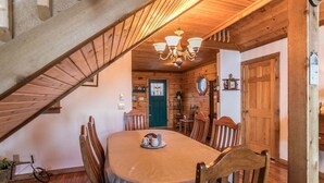 A dining area with a table, chairs, a chandelier, a staircase, and wooden walls. - Meagan's Loft (Banner Elk)