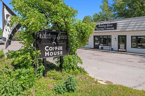 Une enseigne indiquant l’emplacement du café Pedaling Beans, avec une vue dégagée sur l’entrée du bâtiment et le parking.