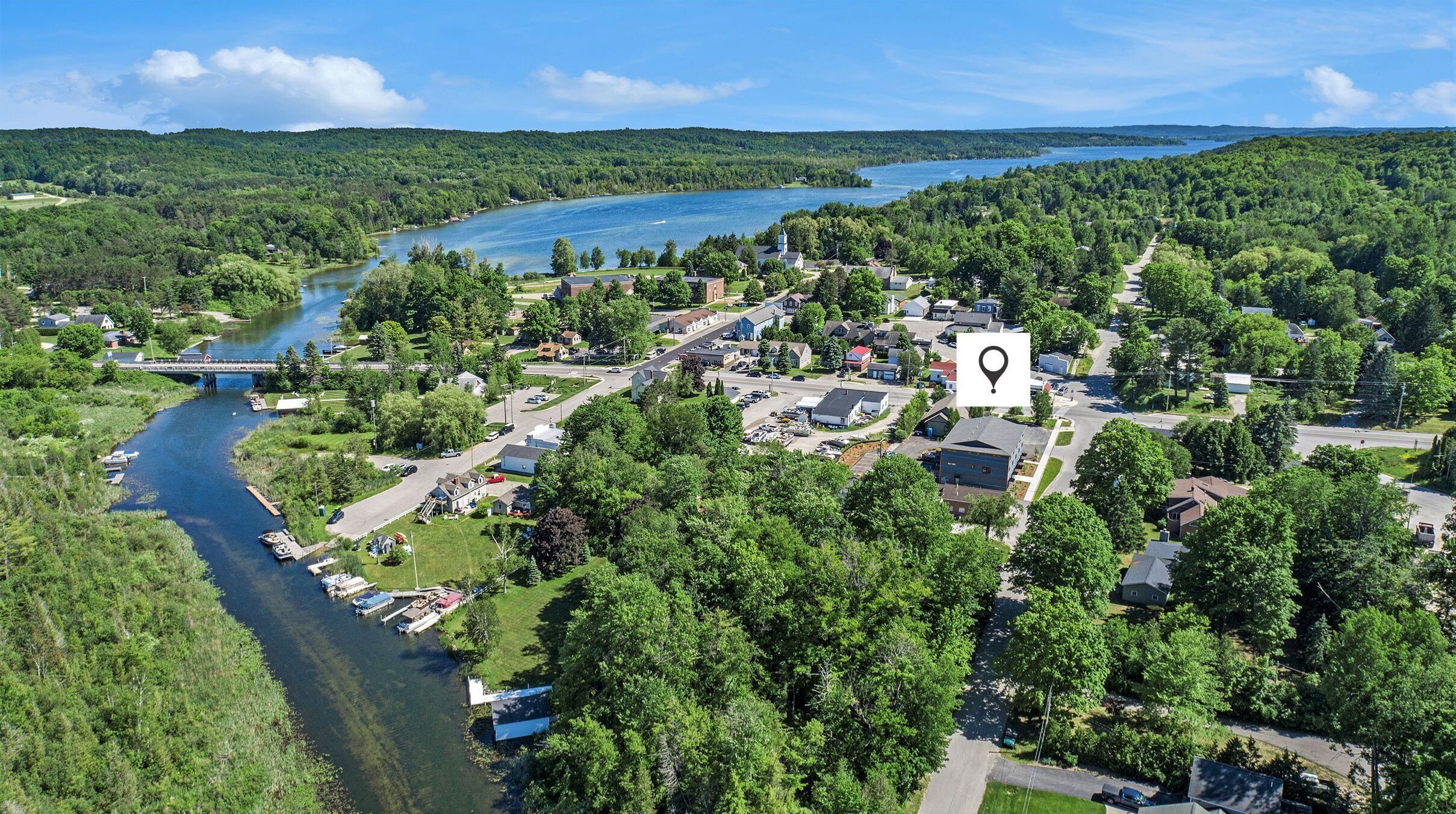 An aerial view of a lakeside community with a prominent church, a bridge, and a boat dock.