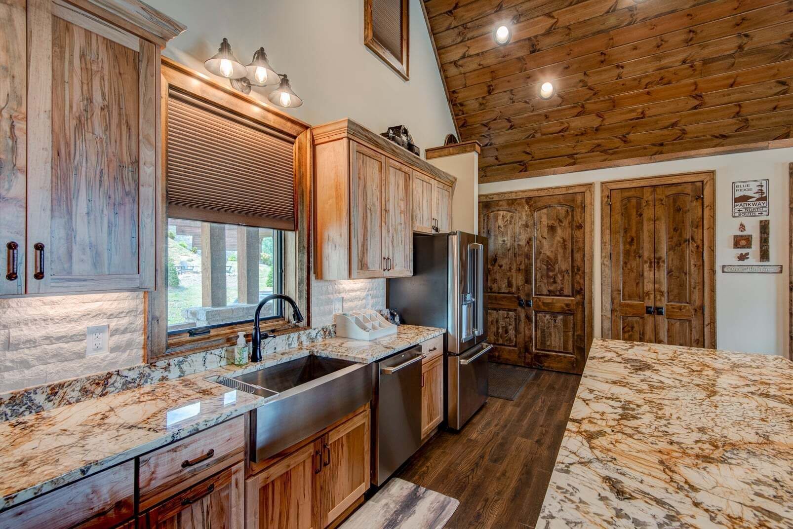A kitchen with wooden cabinets, a stainless steel refrigerator, and a marble countertop.