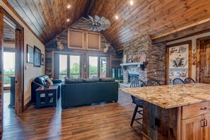 A spacious living area with a fireplace, wooden ceiling, and large windows. - Lucky 7 at Eagles Nest (Banner Elk)