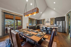 A modern kitchen with a dining area, large windows, and a hanging light fixture. - Golden Sunsets at Eagles Nest (Banner Elk)
