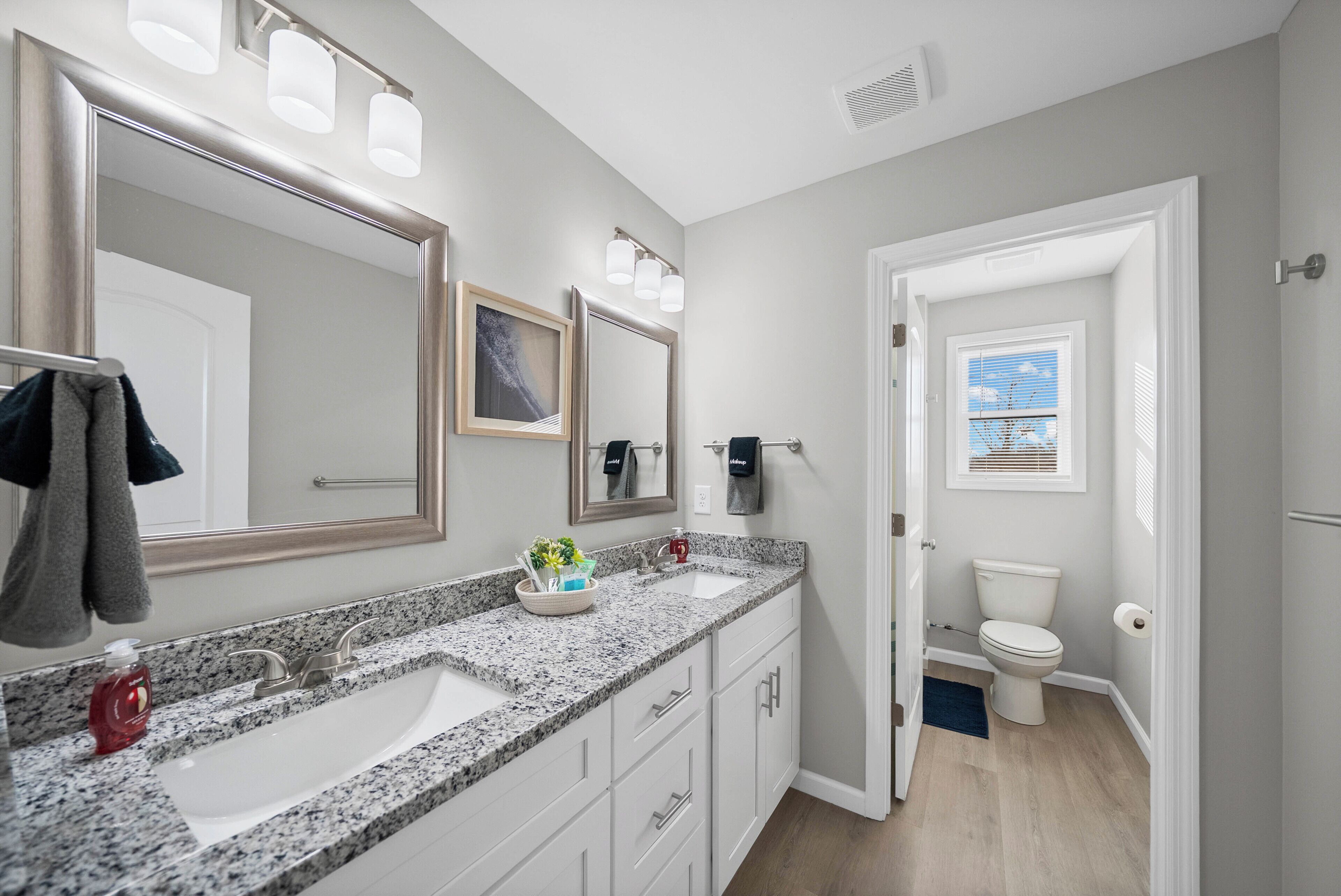 A bathroom with a granite countertop sink, a large mirror, and a toilet.