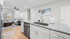 A modern kitchen with granite countertops, stainless steel appliances, and a dining area with a sofa and coffee table. - The Lookout (Clarksville)