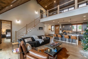 A spacious living area with a staircase, a kitchen with bar stools, and a Christmas tree. - Mountain Time Lodge at Eagles Nest (Banner Elk)