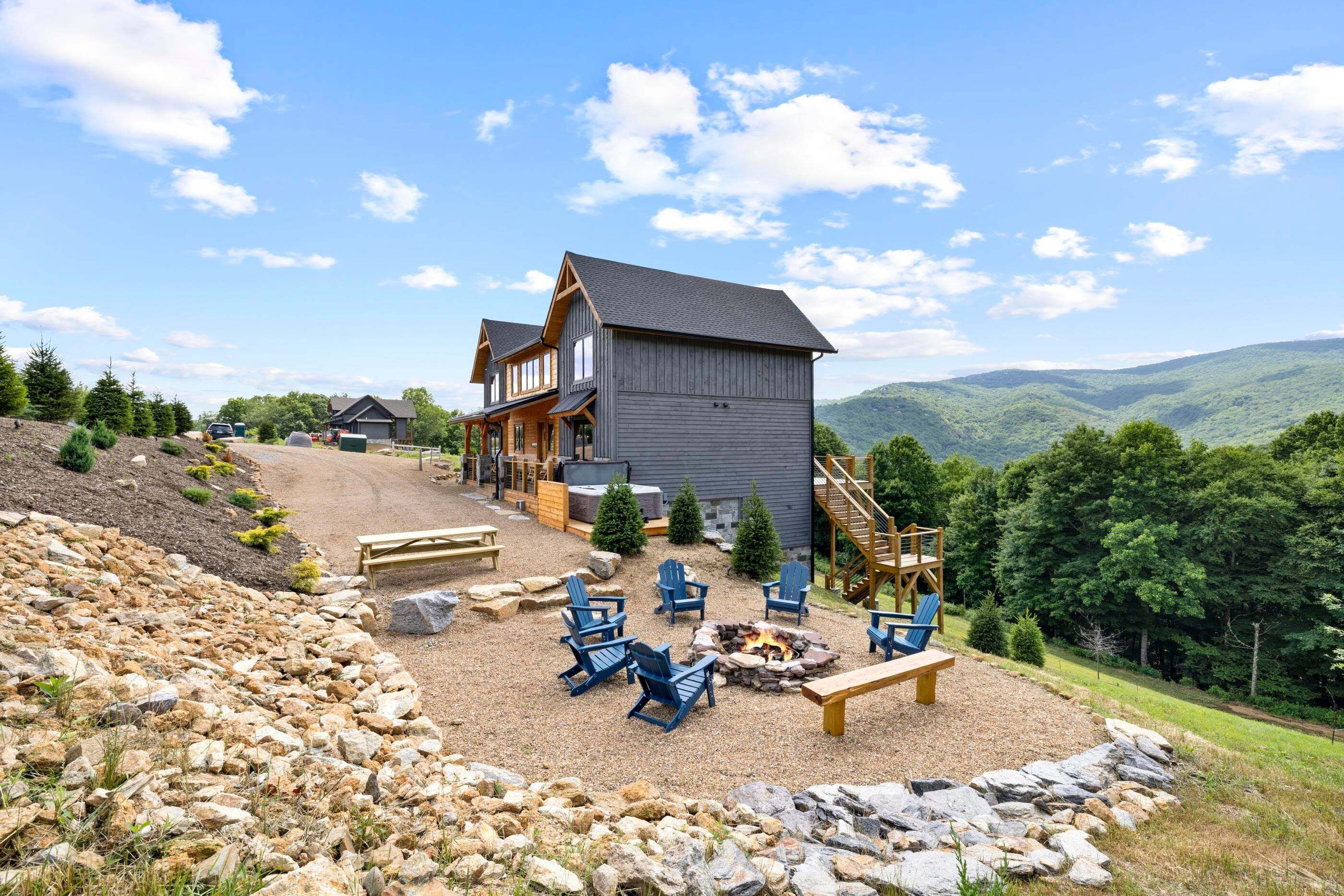 A lodge with a fire pit, outdoor seating, and a scenic mountain backdrop.