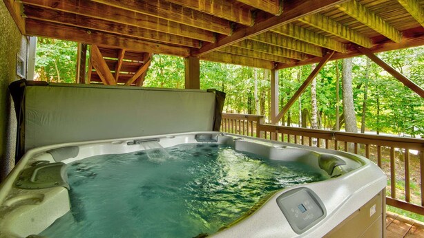 Ein Whirlpool mit Holzterrasse und Blick auf einen Wald.