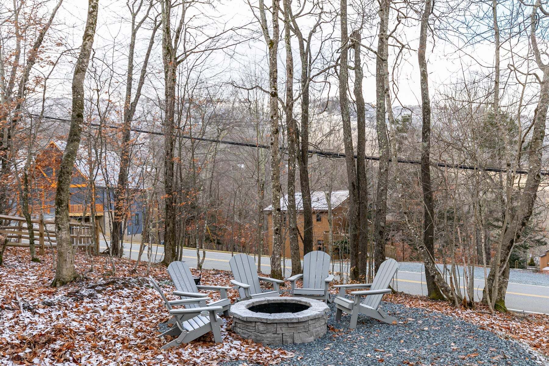 Une zone boisée avec un foyer en pierre et plusieurs fauteuils Adirondack.