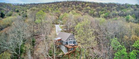 A house with a deck, surrounded by forest.