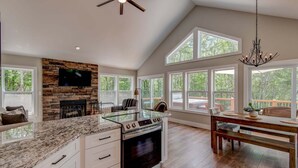 A spacious kitchen with a stone fireplace, a large island, and a dining area with a view. - Lessons From Mars (Banner Elk)