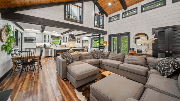 A spacious living area with a large sectional sofa, wooden flooring, and a high ceiling with exposed beams. - The Beech House (Banner Elk)