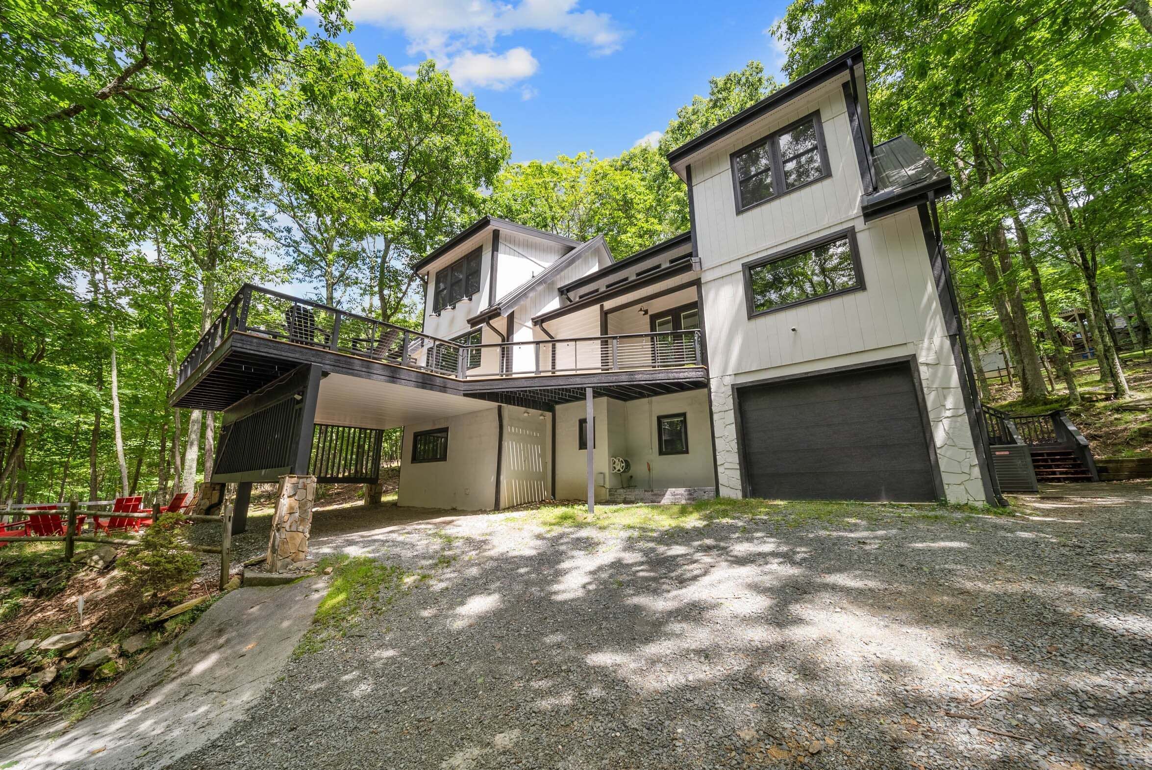 A two-story house with a covered porch, a garage, and a gravel driveway.
