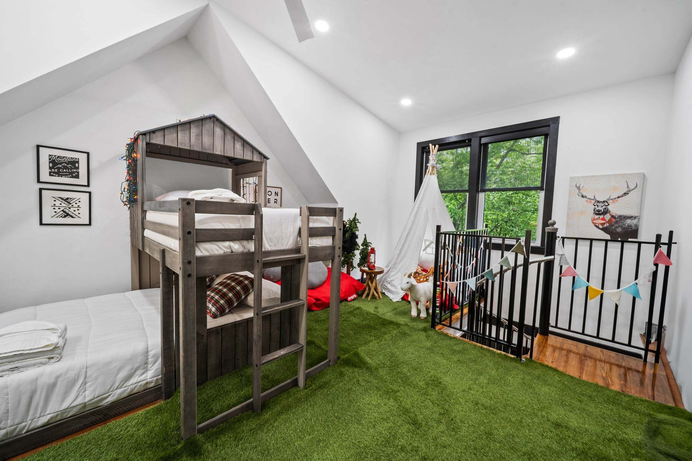 Een kamer met stapelbedden, een raam met uitzicht en een witte muur met ingelijste foto's.