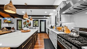 A modern kitchen with a large island, stainless steel appliances, and pendant lighting. - The Beech House (Banner Elk)