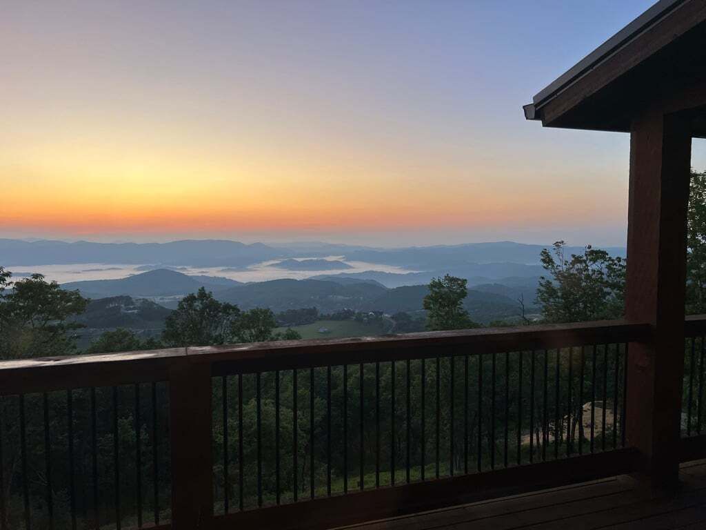 Een houten terras met uitzicht op verre bergen en een heldere lucht.