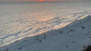 Ein Strand bei Sonnenuntergang, mit Menschen und Zelten.