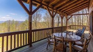 Eine Holzterrasse mit Tisch und Stühlen mit Blick auf ein bewaldetes Gebiet.