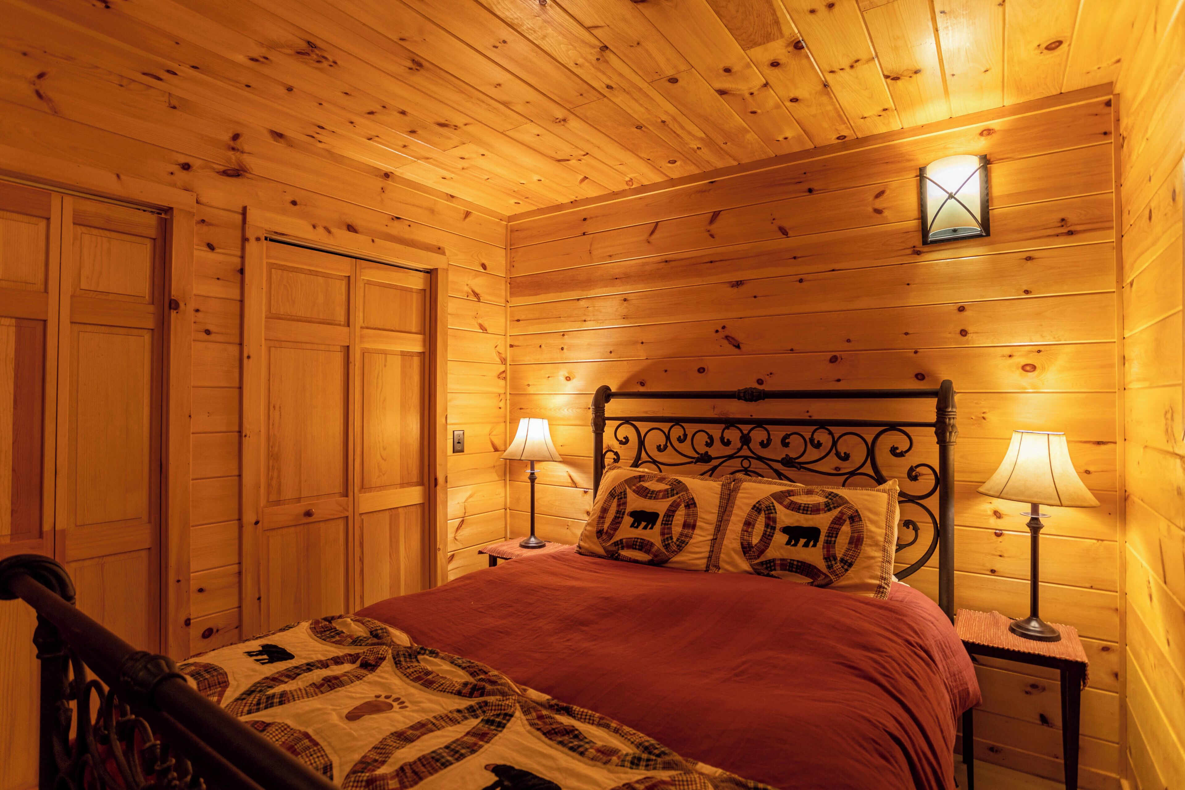 Una habitación con paneles de madera, una cama, dos lámparas de noche y un aplique de pared.