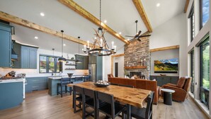 A spacious kitchen with a large island, a dining area with a wooden table and chairs, and a stone fireplace. - Sky's the Limit at Blue Ridge Mountain Club (Boone)