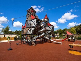 Um parquinho com uma estrutura de escalada e um escorrega.