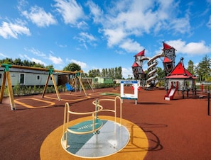 A playground with various play structures, including swings and climbing frames, under a clear blue sky. - Lillardsedge Apartment Sleeps 6 With Parking (Jedburgh)