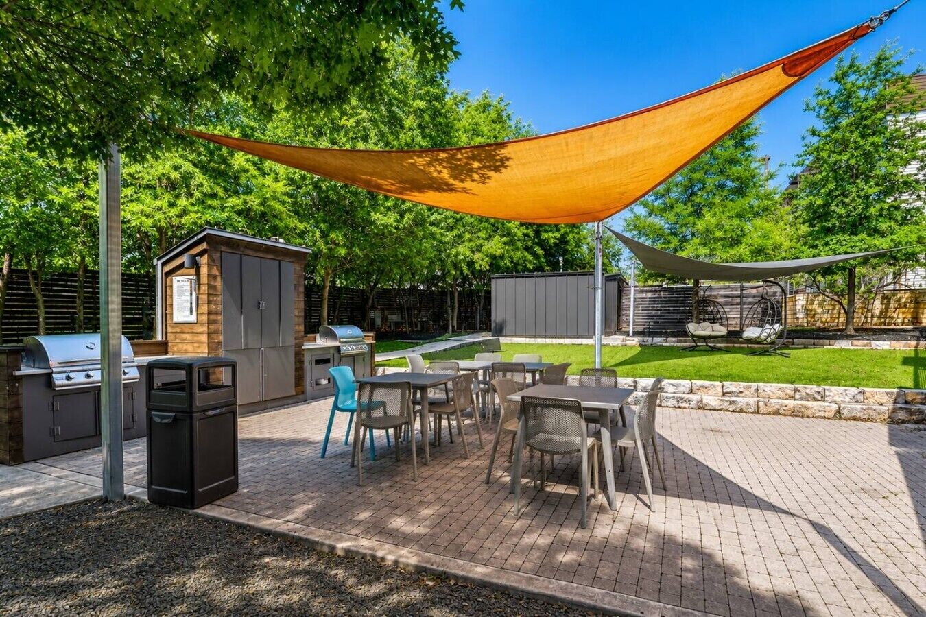 Un patio al aire libre con una parrilla, asientos y una hamaca.