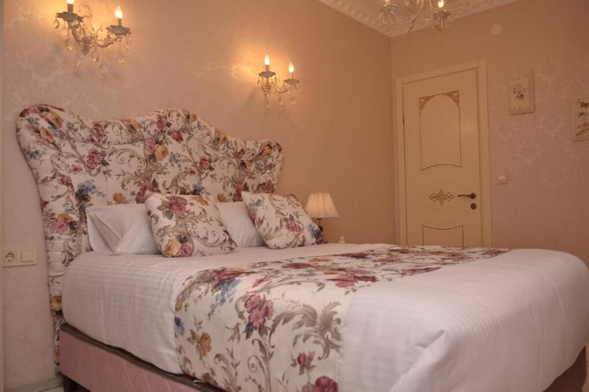 Un dormitorio con colcha estampada de flores, un candelabro y apliques de pared.