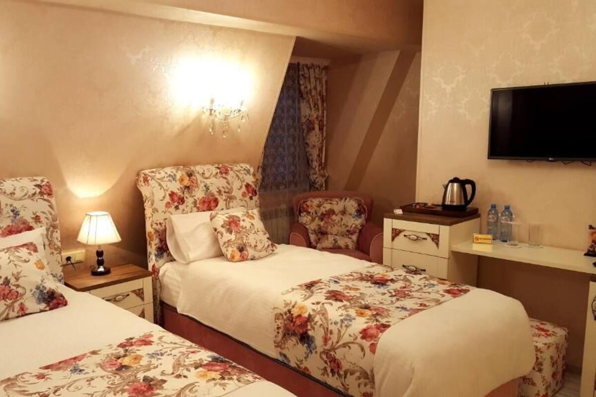 Habitación de hotel con dos camas, un escritorio, un televisor y una araña.