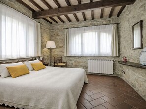 A bedroom with a bed, a chair, a lamp, a radiator, and stone walls. - Gli Archi by Interhome (Rufina)