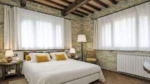 Ein Schlafzimmer mit einem Bett, zwei Nachttischen, einer Lampe, einem Sessel und einem Heizkörper.