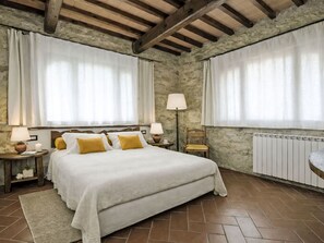Ein Schlafzimmer mit einem Bett, zwei Nachttischen, einer Lampe, einem Sessel und einem Heizkörper.