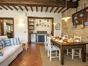 A cozy living room with a dining area, a kitchen, and a stone wall with decorative plates. - Le Mangiatoie by Interhome (Rufina)