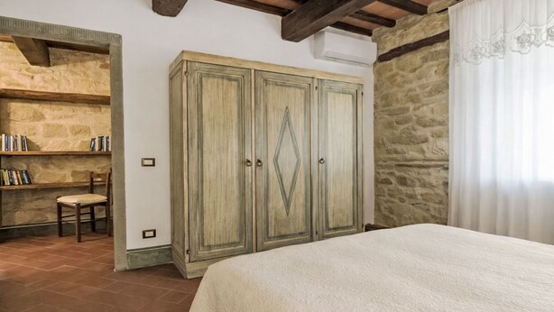 Een slaapkamer met een bed, een kledingkast, een stoel en een boekenkast.
