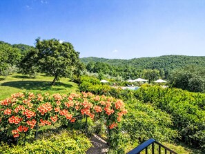 Ein üppiger Garten mit Laube, Schwimmbad und Blick auf sanfte Hügel.