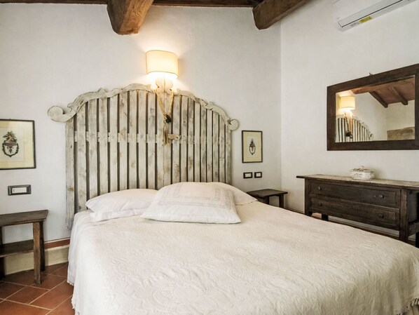 Ein Schlafzimmer mit einem Holzkopfteil, einem Nachttisch, einer Kommode und einer Wandleuchte.