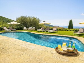 A swimming pool with lounge chairs and umbrellas, surrounded by greenery and mountains. - La Noce by Interhome (Rufina)