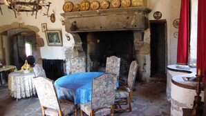 A room with a fireplace, floral-patterned chairs, a table with a blue tablecloth, and a chandelier. - Chateau de Vermette: wedding, seminars, master class, long term rental possible (Argentonnay)