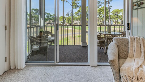 A room with a sliding glass door leading to a balcony with outdoor furniture. - Condo in Sea Trail, GREAT GOLF view, Restaurants on site, pool at the complex.  (Sunset Beach)