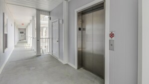 A corridor with an elevator, doors, and an exit sign. - Condo in Sea Trail, GREAT GOLF view, Restaurants on site, pool at the complex.  (Sunset Beach)