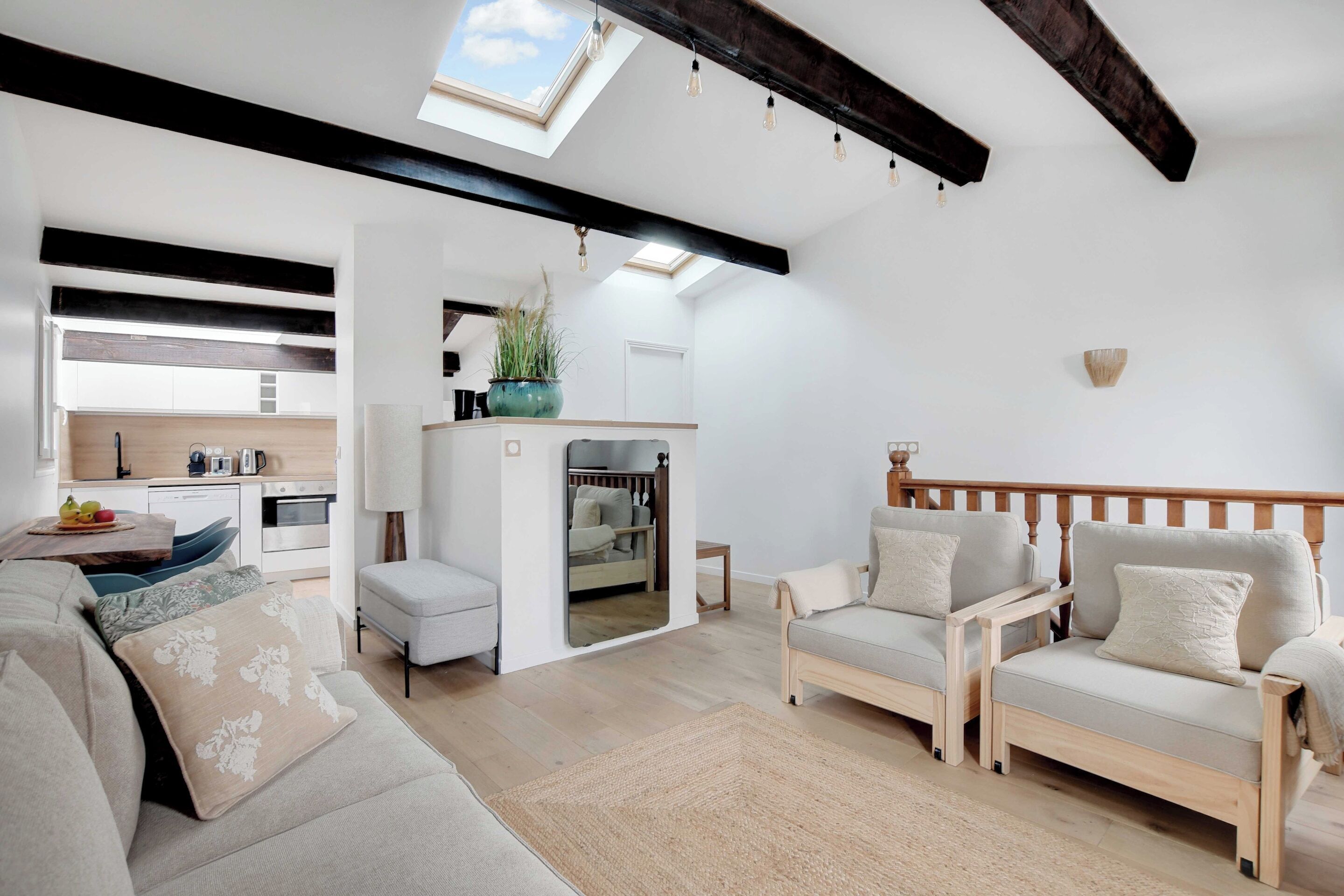 Una sala de estar moderna con sofá, sillones, una mesa de centro y una cocina al fondo.
